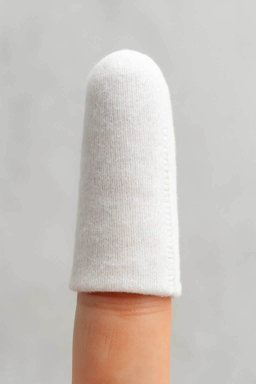 White finger sleeve on a finger against a gray background
